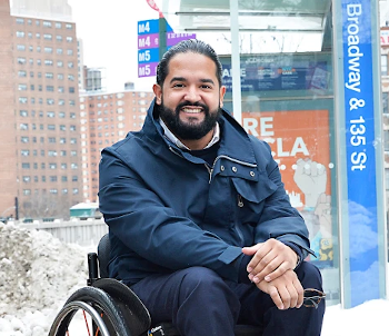 Quemuel Arroyo sitting at a bus stop in his wheelchair
